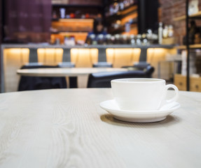 Coffee cup on tavble with blurred counter bar cafe backgrou