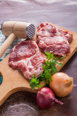 Raw pork chops on a wooden cutting board