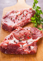 Raw pork chops on a wooden cutting board