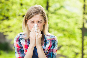 Woman with allergy symptom blowing nose - obrazy, fototapety, plakaty