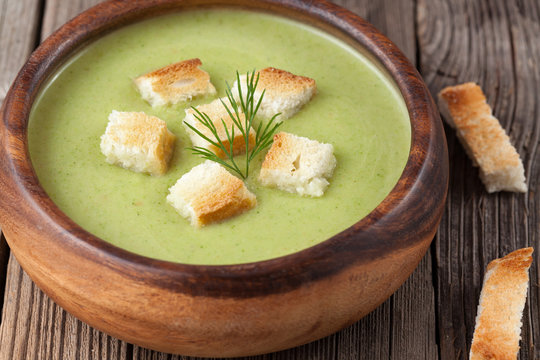 Healthy green cream broccoli soup with dried crusts in bowl