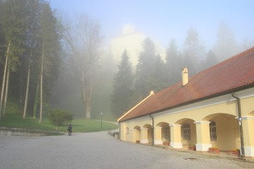 Fototapeta premium Castle in the fog and man on the path