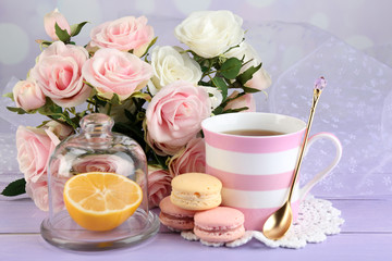 Colorful macaroons with cup of tea on wooden background