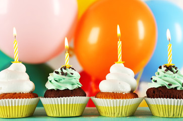 Delicious birthday cupcakes on table on bright background