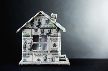 Money house on table on gray background
