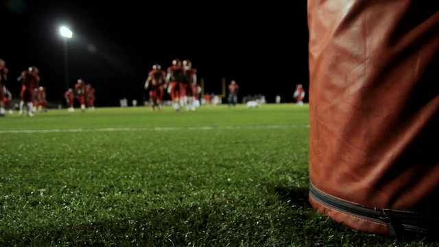 Behind a goalpost as football players warm up before a game.