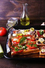 Different sandwiches with vegetables and cheese on pan on table close up