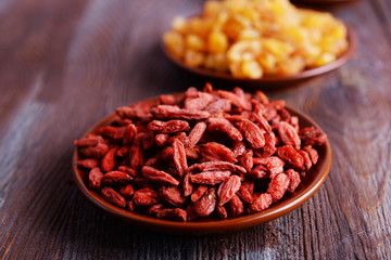 Raisins and Goji in small plates on rustic wooden table background