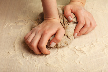 Making dough by female hands on wooden table background