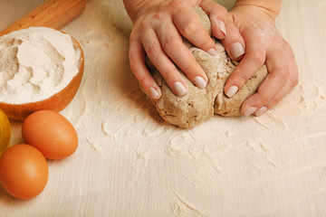 Making dough by female hands on wooden table background