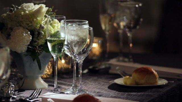 A set table in with a light shinning on a group of glasses.