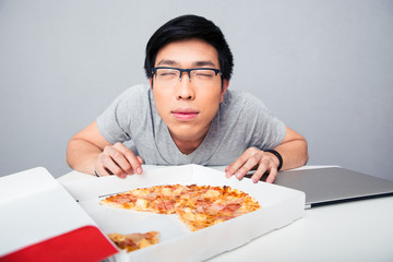 Young asian man smelling pizza