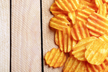 Delicious potato chips on wooden table close-up