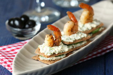Appetizer canape with shrimp and cucumber on plate on table close up