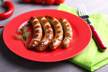 Grilled sausages on plate with vegetables on table close up