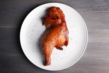 Smoked chicken leg on plate on wooden background