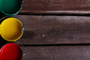 Metal buckets with colorful paint on wooden background