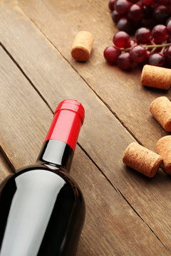 Glass bottle of wine with corks and grapes