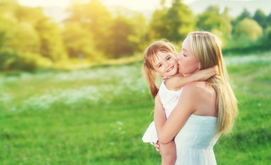 Obraz premium happy family on nature mother kissing little daughter
