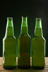 Glass bottles of beer on dark green background