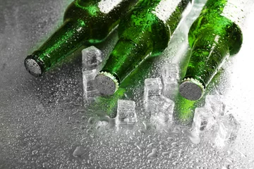 Foto op Canvas Glass bottles of beer with ice cubes on wet table background © Africa Studio