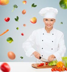 smiling female chef chopping vegetables