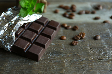 Chocolate with mint and coffee beans on wooden background