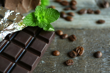 Chocolate with mint and coffee beans on wooden background