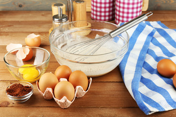 Preparation cream with eggs in glass bowl on wooden background