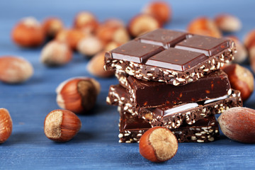 Pieces of chocolate with hazelnut on wooden table, closeup