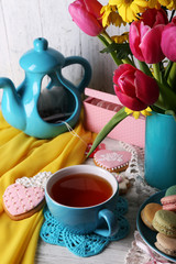 Composition of spring flowers, tea and cookies on table