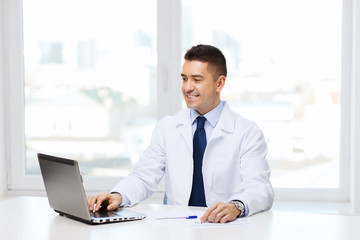 smiling male doctor with laptop in medical office