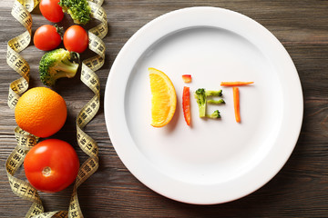 Word DIET made of sliced vegetables in plate with measuring