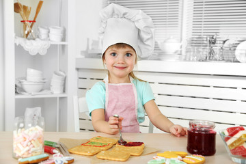 Little girl preparing cookies in kitchen at home
