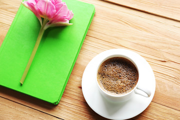 Cup of coffee with notebook and fresh flower
