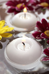 Bowl of spa water with flowers and candles, closeup