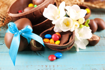 Obraz na płótnie Canvas Chocolate Easter eggs with flowers on wooden table, closeup
