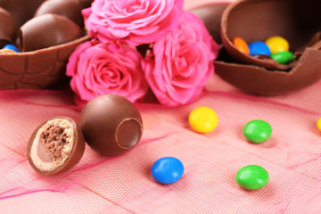 Obraz na płótnie Canvas Chocolate Easter eggs with flowers on color tulle, closeup