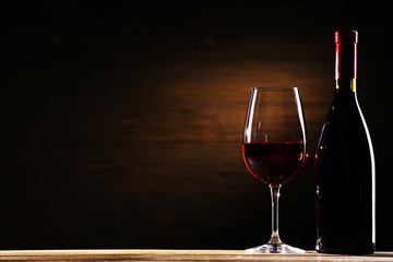 Wineglass and bottle on wooden background