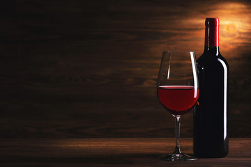 Wineglass and bottle on wooden background
