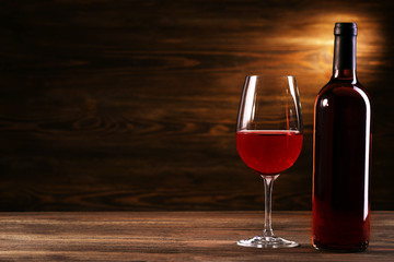 Wineglass and bottle on wooden background