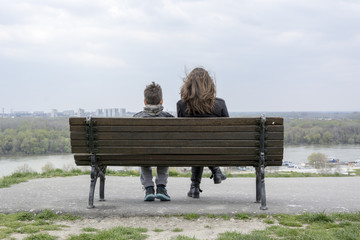 Brother and sister resting on a bench and watch the river