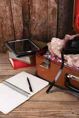 Packing suitcase for trip on wooden background