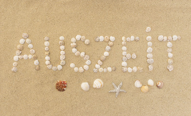 Fototapeta na wymiar Wort AUSZEIT aus Schneckenhäuschen im Sand