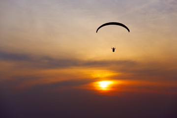 Paraglider silhouette against the background of the sunset sky