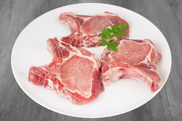 côtelettes de porc crues sur assiette fond bois