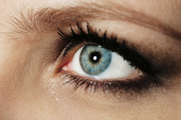 Fototapeta na wymiar Eye of young woman with tear drop close up