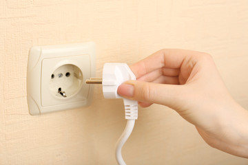 Hand putting plug in electricity socket close up