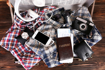 Packed suitcase of vacation items on wooden table, top view