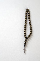 rosary beads hanging against white wall